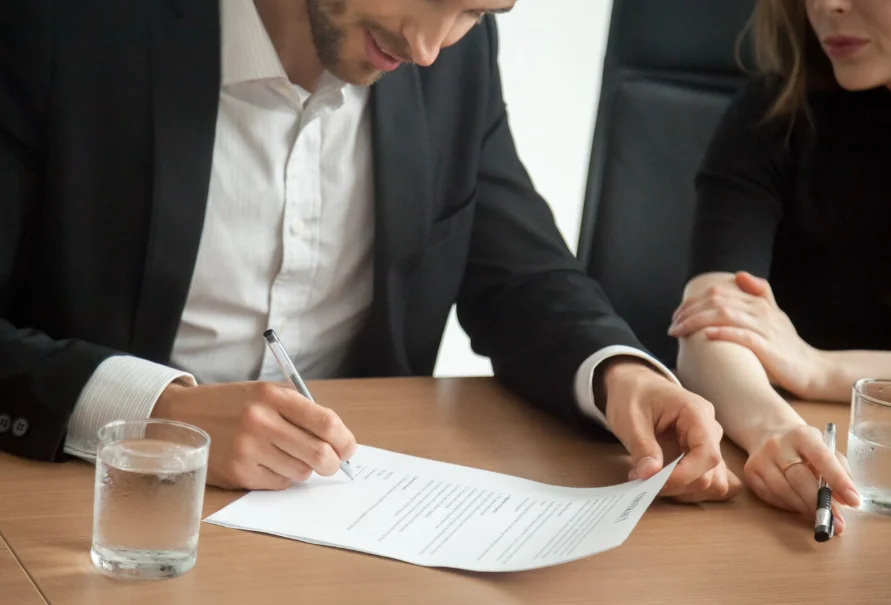 Abogado de contratos revisando y firmando un acuerdo con clientes